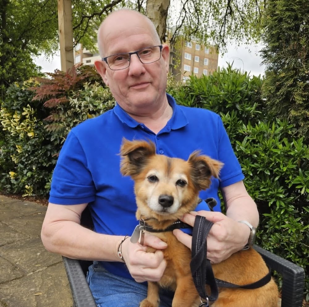 Keith in a blue polo shirt holding his dog Enzo
